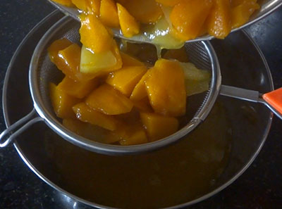 draining the cooked water for mango frooti juice or maaza juice